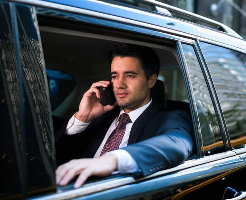 Professional businessman traveling in a luxury limo, staying connected while heading to Toronto Pearson Airport for a seamless and comfortable ride