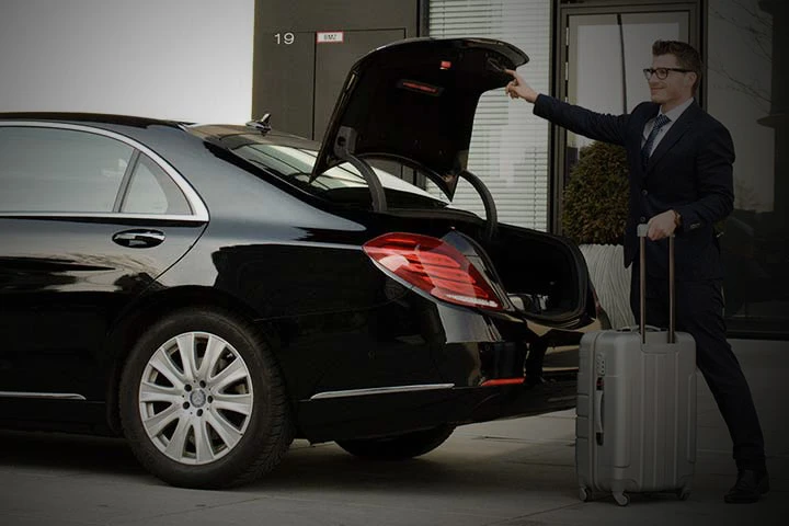 Business traveler loading luggage into an airport limo service car in Toronto.
